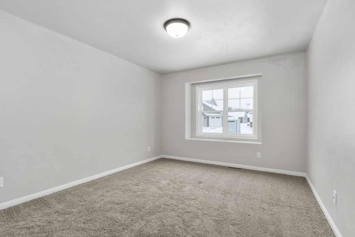 Empty bedroom with carpeted floor, neutral walls, and single window in a Fox Cities home