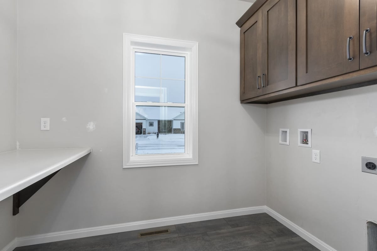 Laundry room with upper cabinets, countertop workspace, window, and tile flooring in a Fox Cities home