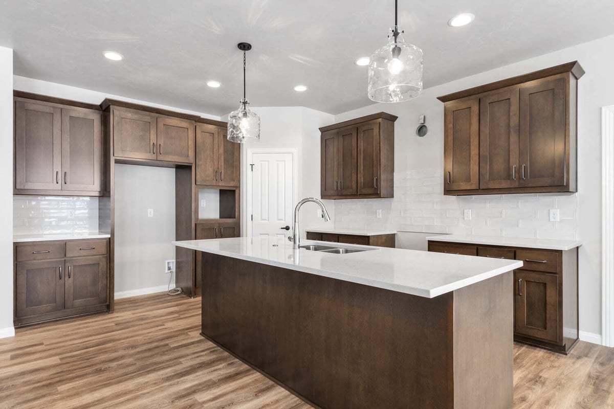 Modern kitchen with large island, white countertops, wood cabinetry, and pendant lights in a Fox Cities home
