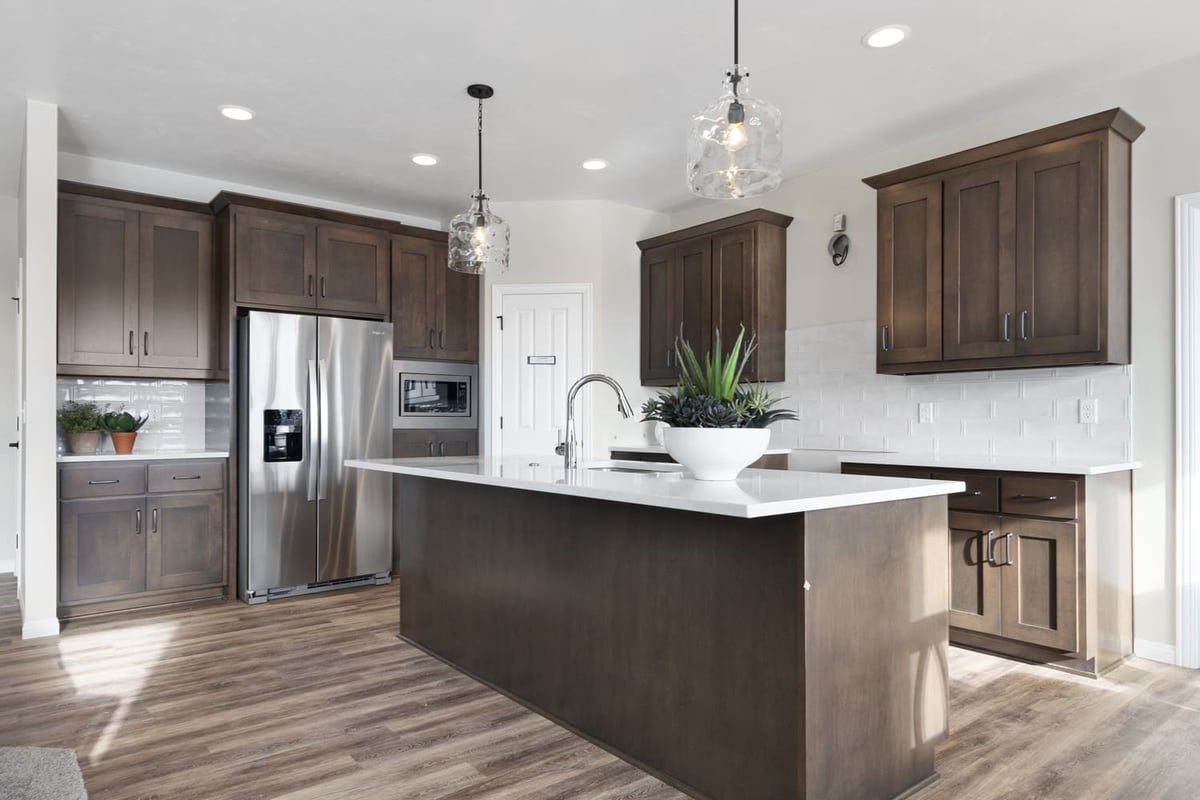 Modern kitchen with large island, white countertops, wood cabinets, and pendant lighting in the Fox Cities