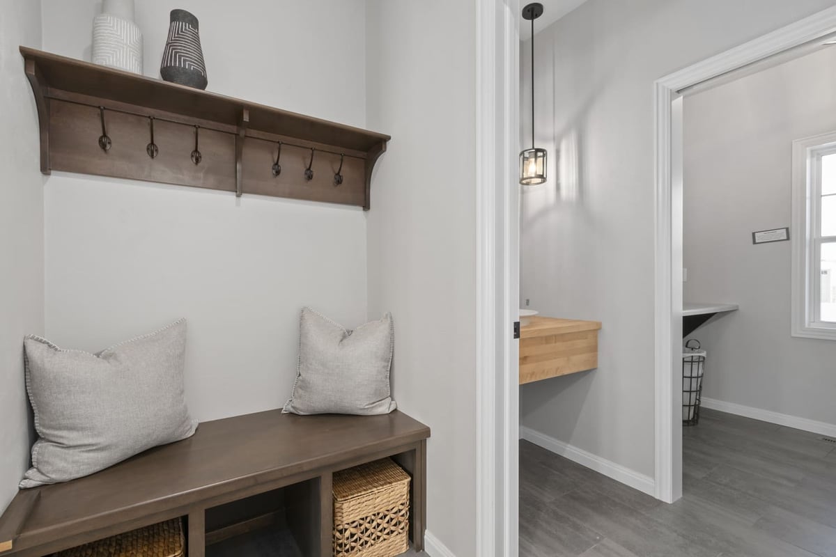 Mudroom bench with hooks, cubbies, and adjacent powder room in a Fox Cities home