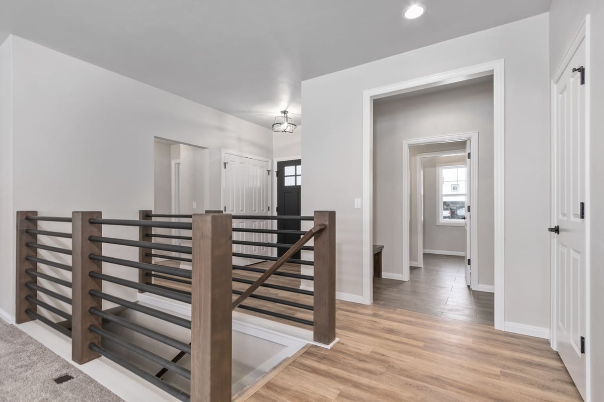 Open hallway with wood flooring, modern railing, and views into adjacent rooms in a Fox Cities home