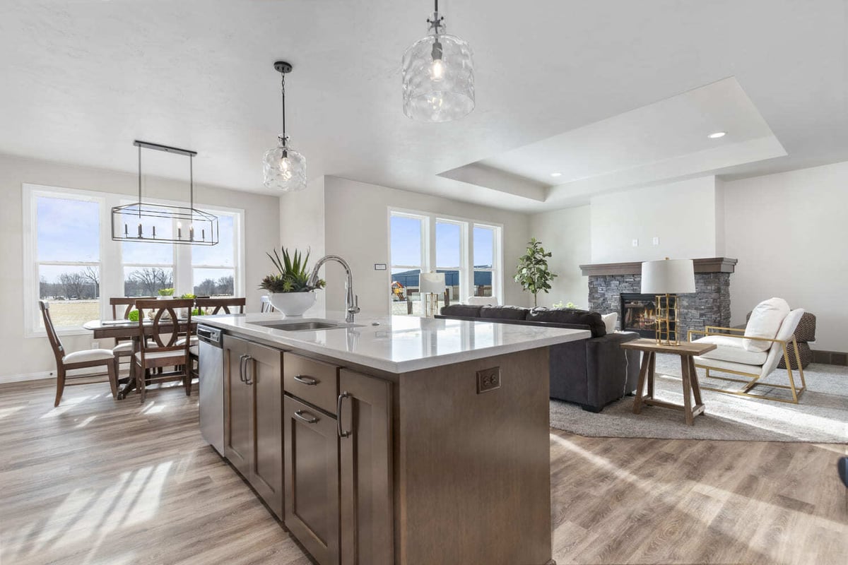 Open kitchen and living area with large island, pendant lighting, dining space, and fireplace in the Fox Cities