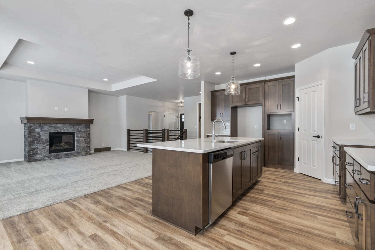 Open kitchen and living area with large island, pendant lights, and stone fireplace in the Fox Cities
