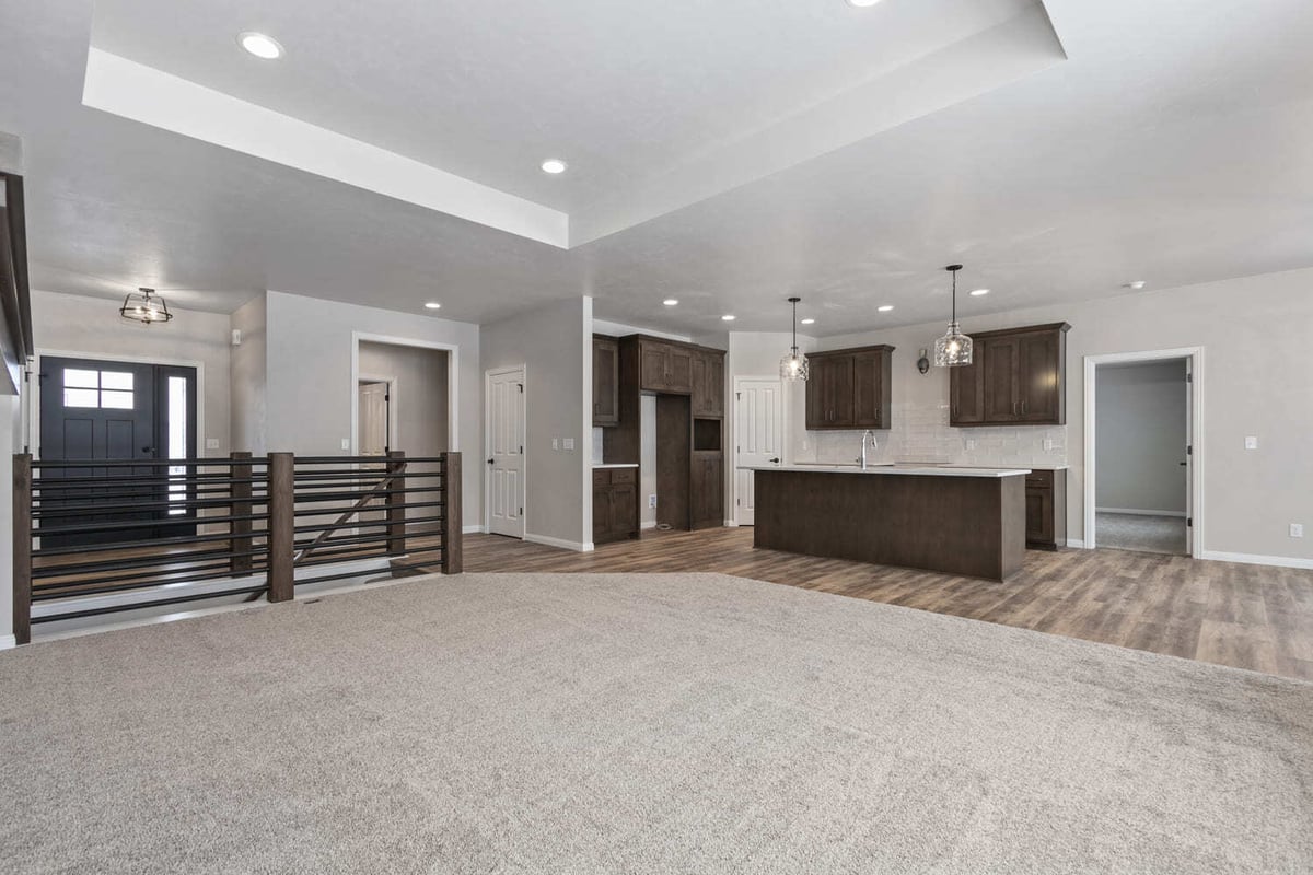 Open-concept living area with kitchen island, pendant lights, and railing detail in the Fox Cities
