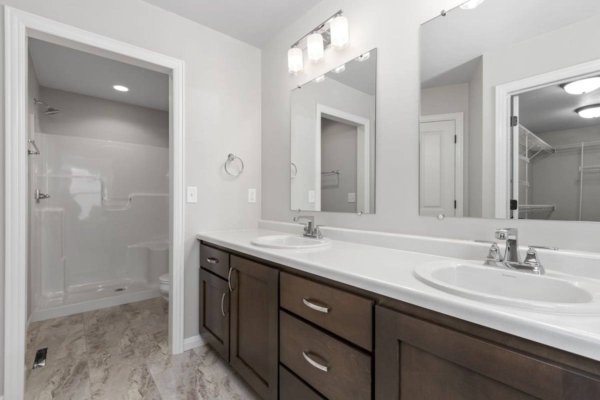 Primary bathroom with double-sink vanity, large mirrors, and walk-in shower in a Fox Cities home