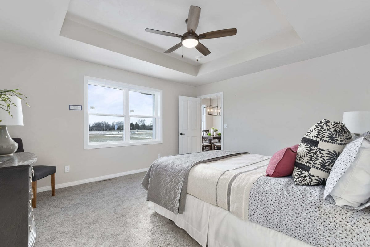 Primary bedroom with tray ceiling, ceiling fan, neutral finishes, and window in a Fox Cities home