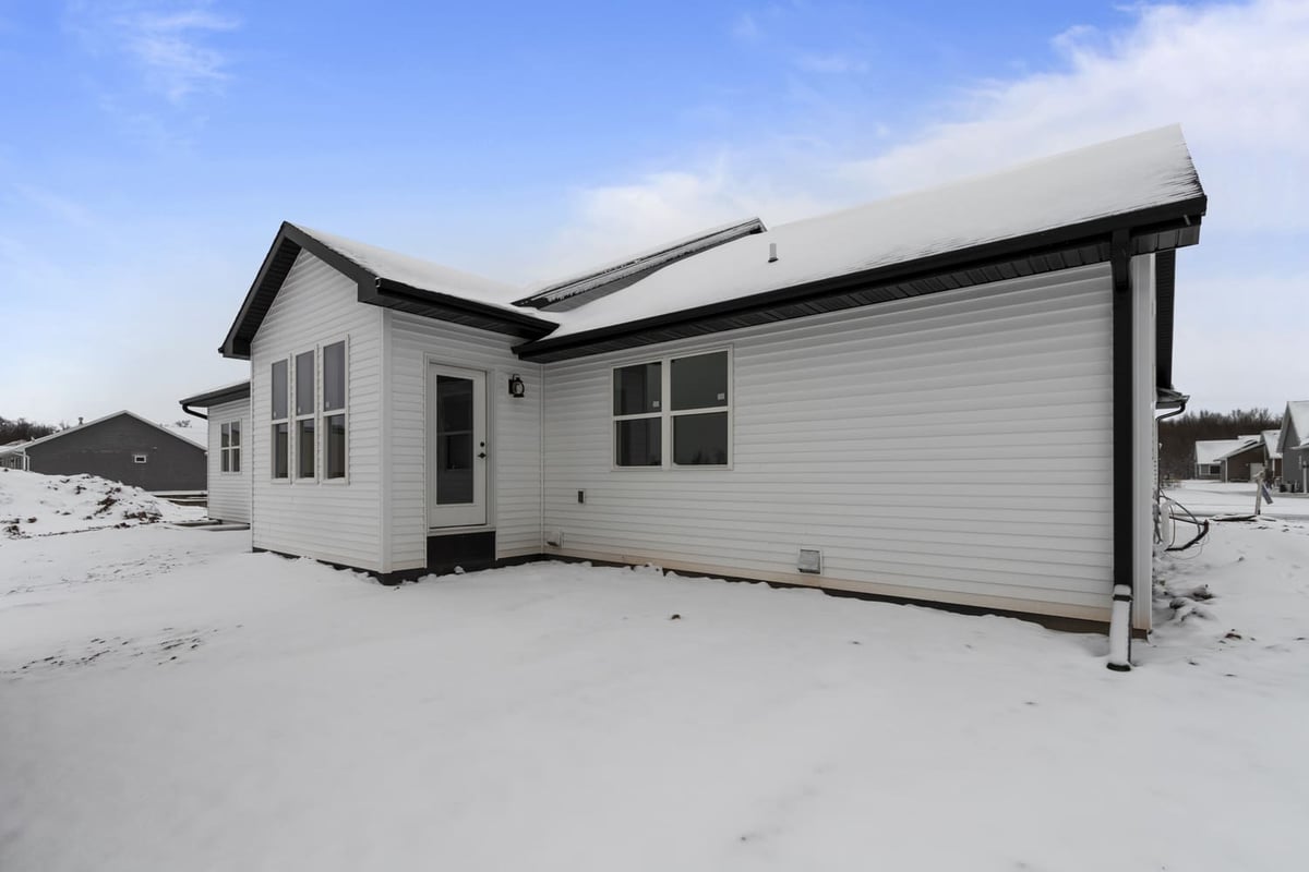 Rear exterior of a single-story home with white siding and snow-covered yard in the Fox Cities