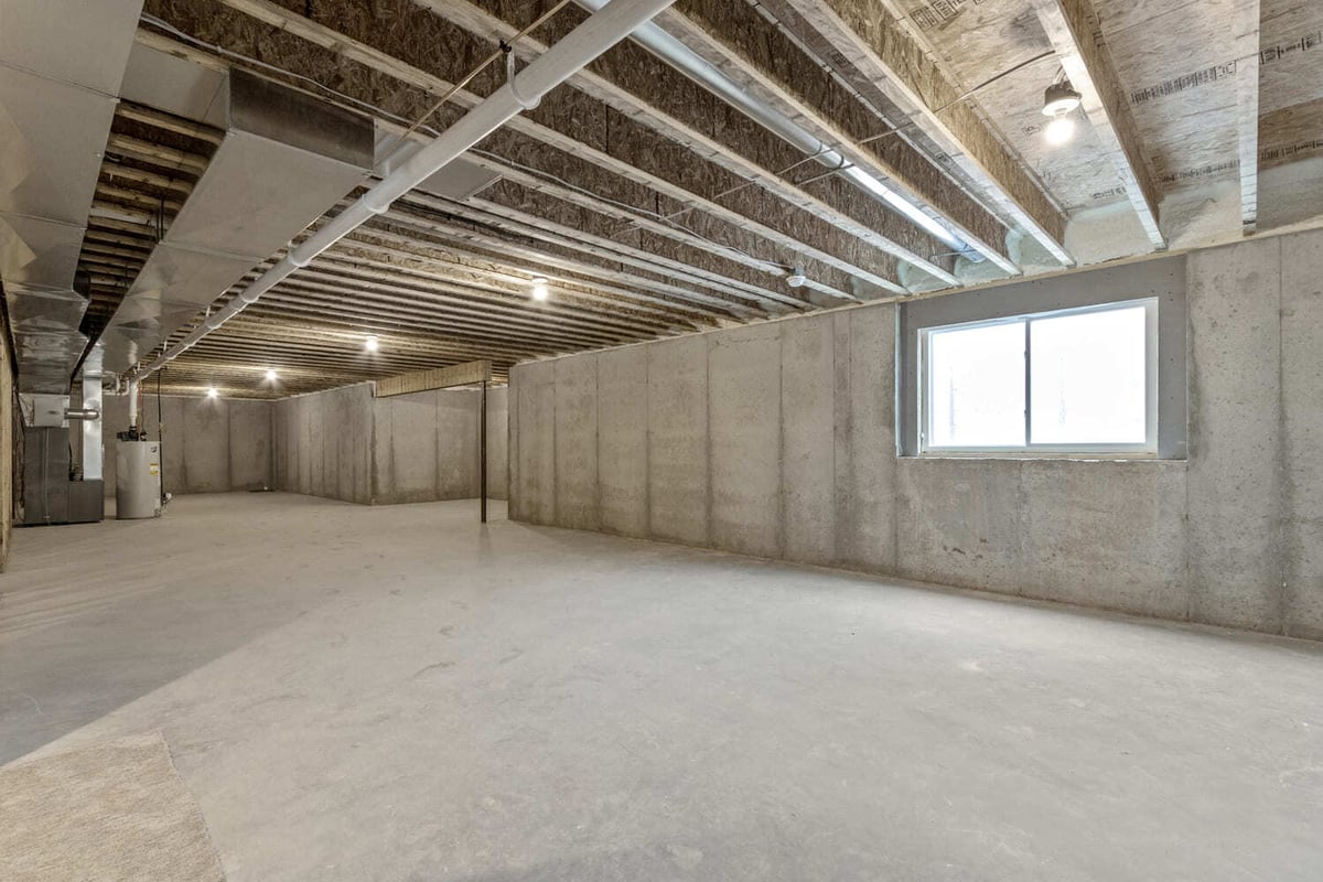 Unfinished basement with concrete floors, exposed ceiling, and window in a Fox Cities home