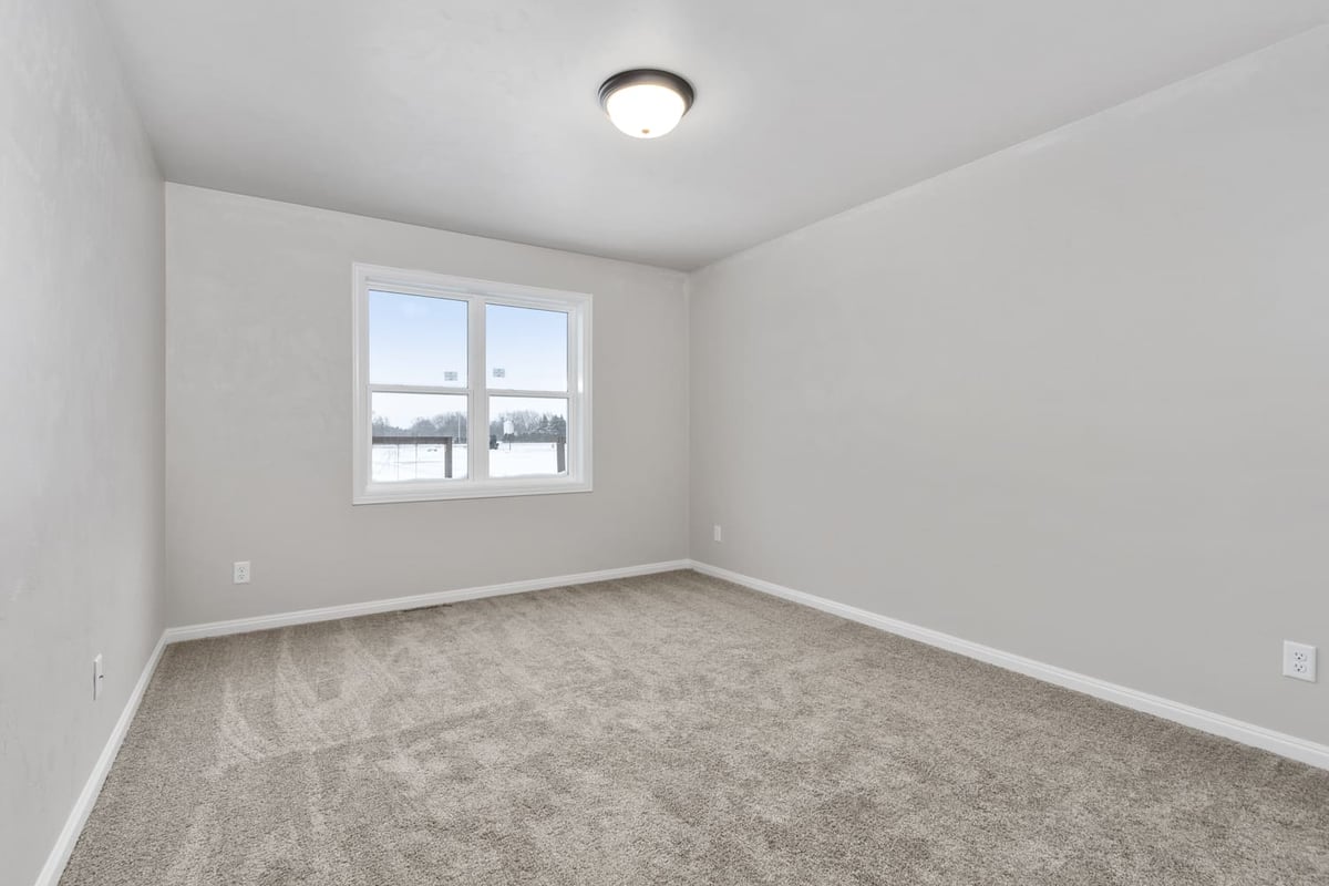 Unfurnished bedroom with carpet, neutral walls, and window overlooking snowy yard in the Fox Cities