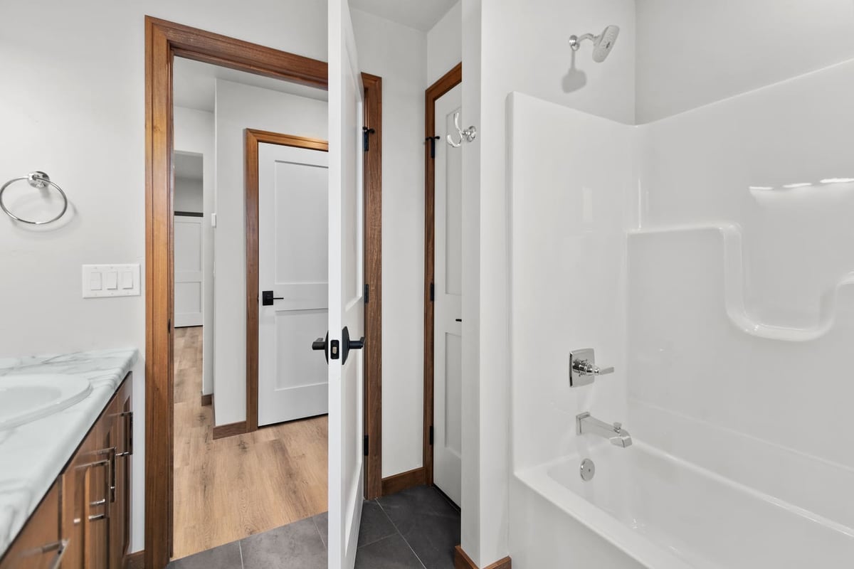 Bathroom with tub and shower combo, white surround, and wood trim in a home located in the Fox Cities