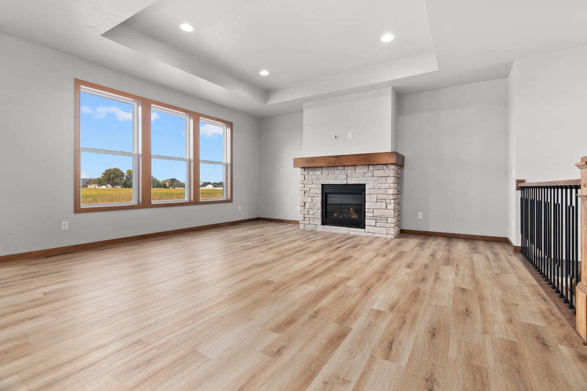 Bright Fox Cities living room with stone fireplace, tray ceiling, and large windows bringing in natural light