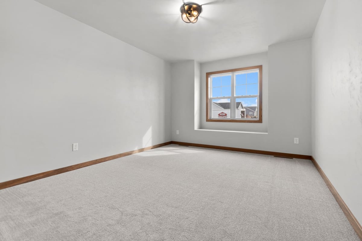 Bright bedroom with carpet flooring, window nook, and wood trim in a home located in the Fox Cities
