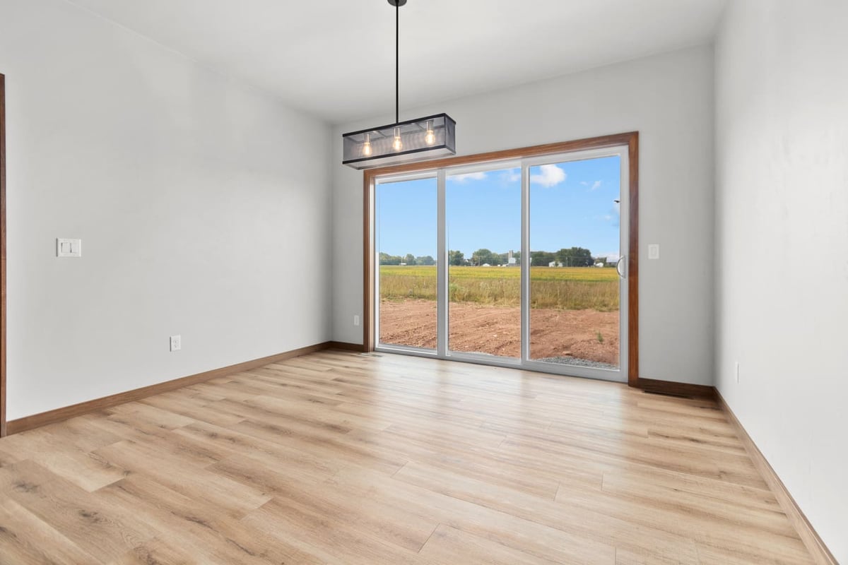 Dining area with wood-look flooring, modern pendant light, and sliding glass doors in a home located in the Fox Cities