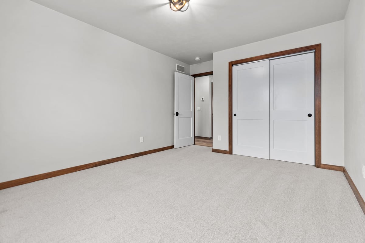 Empty bedroom with carpet, sliding closet doors, and neutral finishes in a home located in the Fox Cities