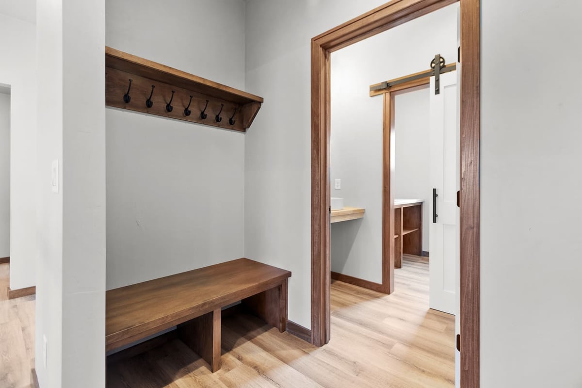 Mudroom with built-in bench, wall hooks, and sliding barn door in a home located in the Fox Cities