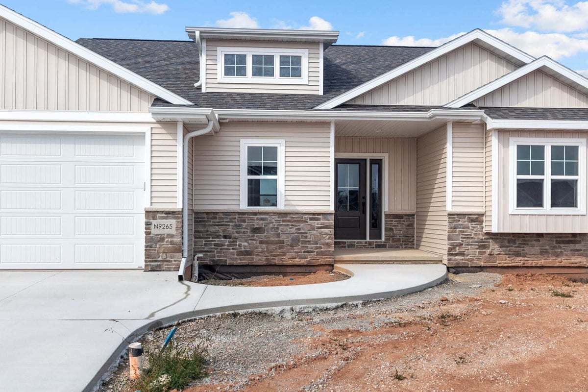 New home exterior with stone accents, beige siding, covered entry, and attached garage in the Fox Cities