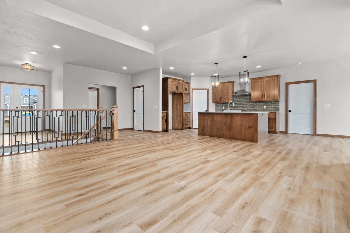 Open-concept Fox Cities living space with kitchen island, wood floors, pendant lights, and large windows overlooking fields