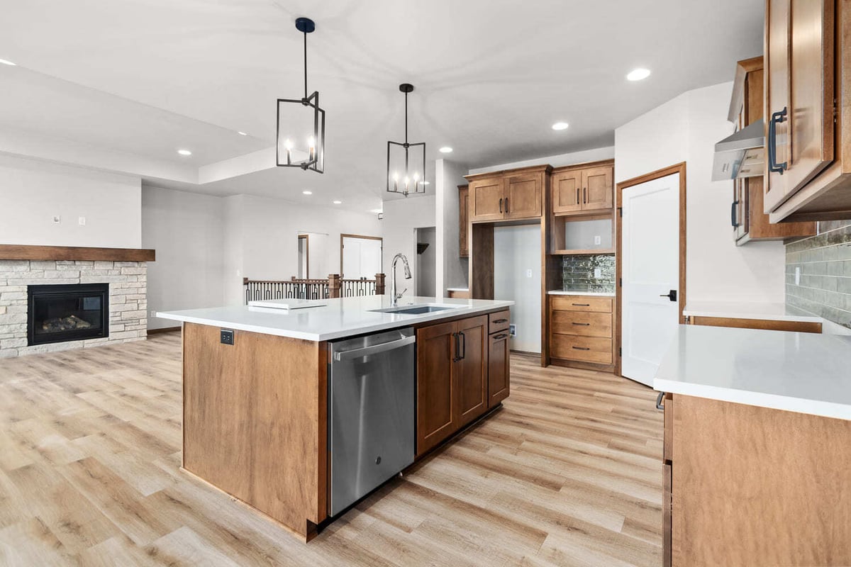 Open-concept kitchen and living area with island, pendant lighting, and stone fireplace in a Fox Cities home