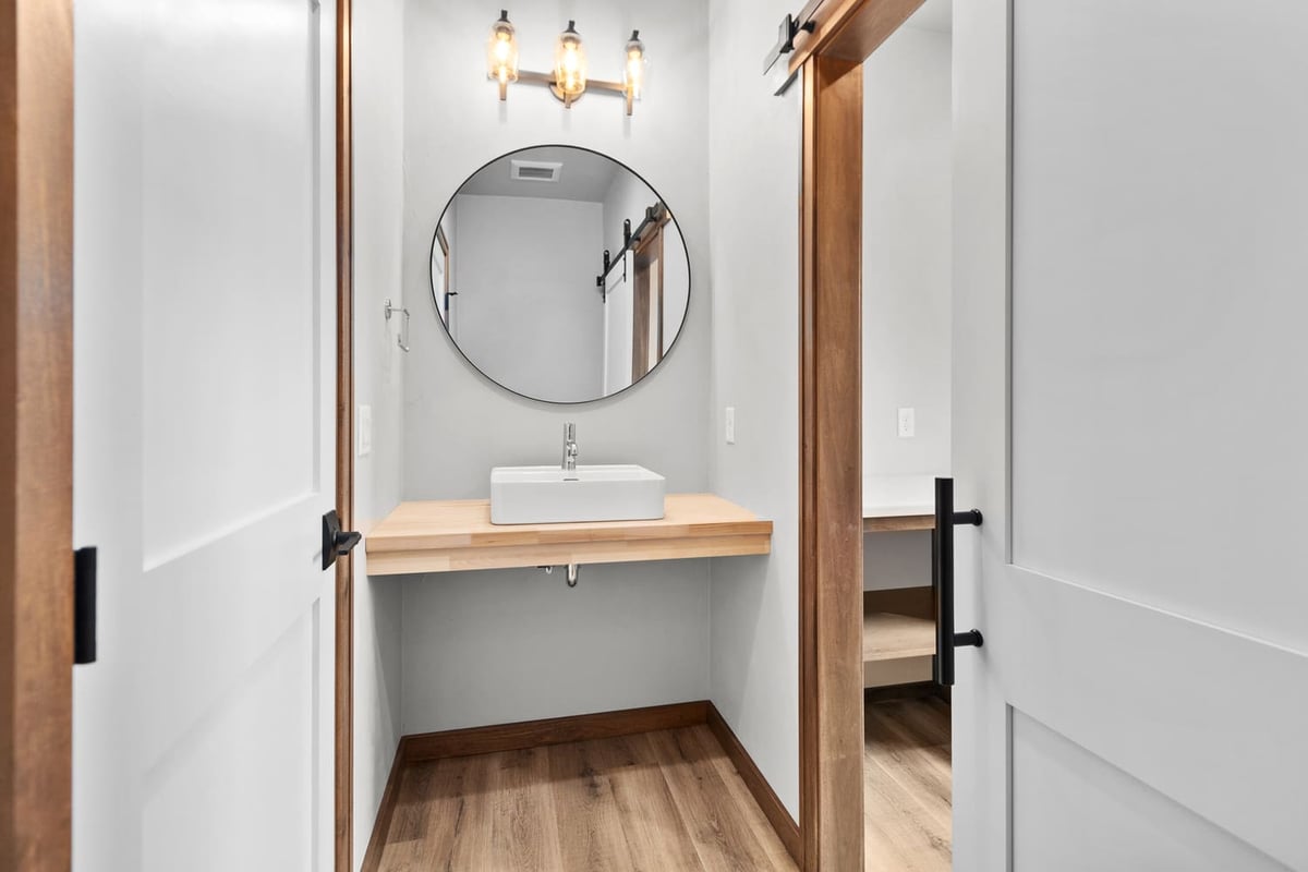 Powder room with floating wood vanity, vessel sink, round mirror, and modern lighting in a Fox Cities home