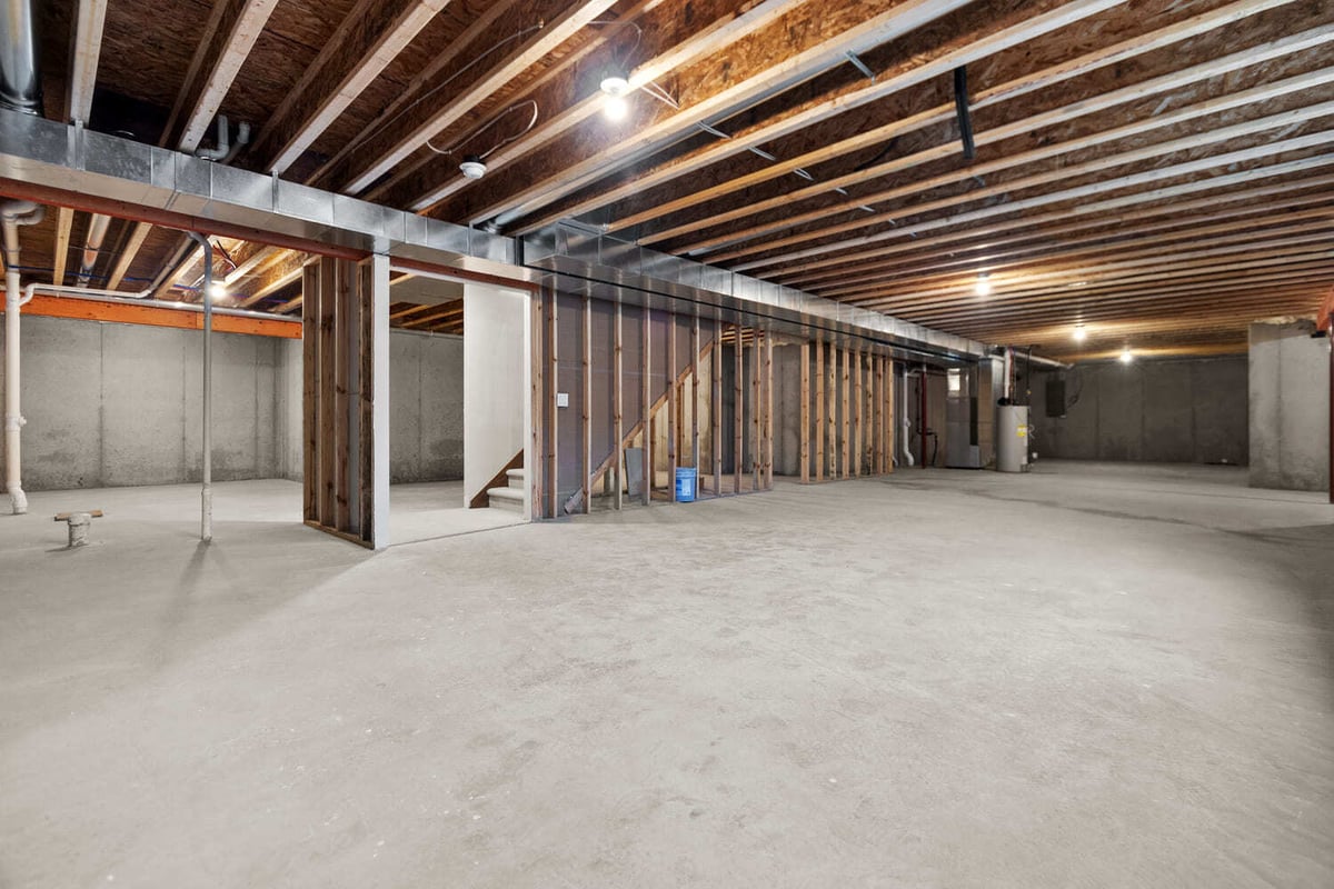 Spacious unfinished basement with exposed framing, ductwork, and stairs in a home located in the Fox Cities