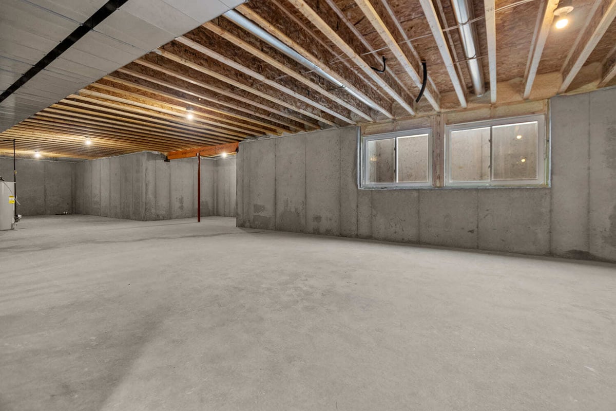 Unfinished basement with concrete floors, exposed beams, and window wells in a home located in the Fox Cities