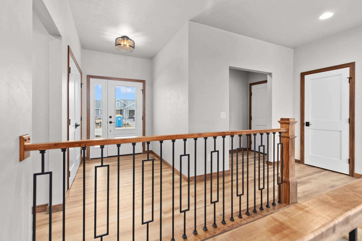 Upper hallway with wood railing, iron balusters, and front entry view in a home located in the Fox Cities