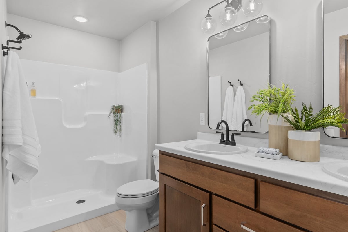 Dual-sink vanity and walk-in shower in a modern bathroom by Midwest Design Homes in Lawrence, WI