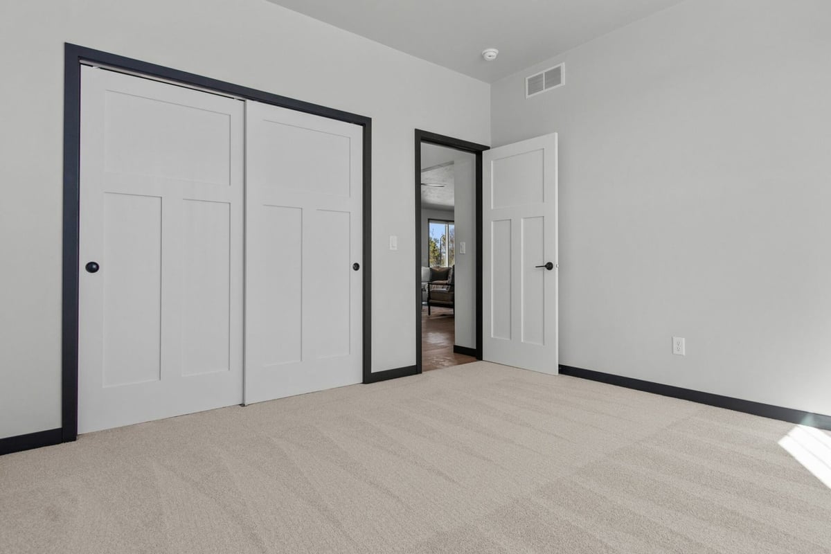 Bedroom with white sliding closet doors in custom home by Midwest Design Homes in Kaukauna, WI