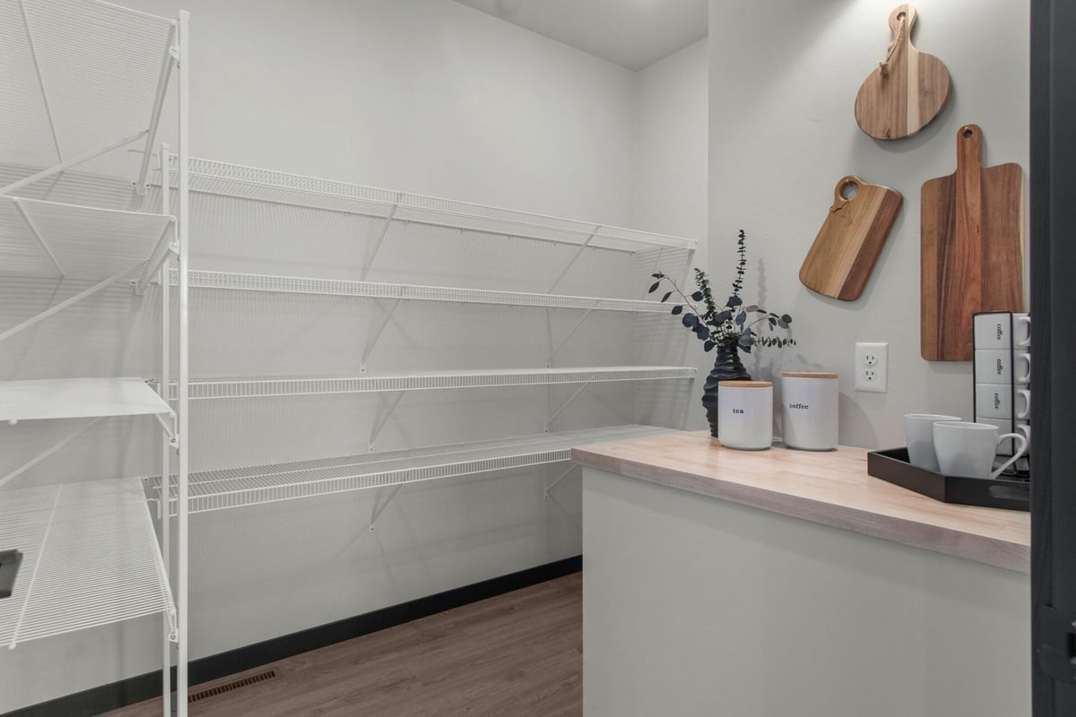 Walk-in pantry with wood countertop and white shelving in a custom home by Midwest Design Homes in Bellevue, WI