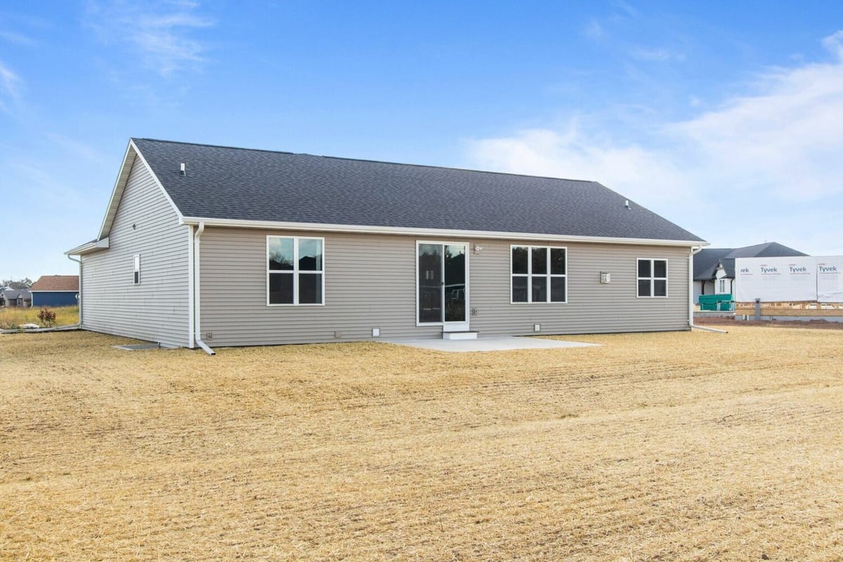 Wide backyard showcasing patio and rear windows of a custom home by Midwest Design Homes in Fremont, WI