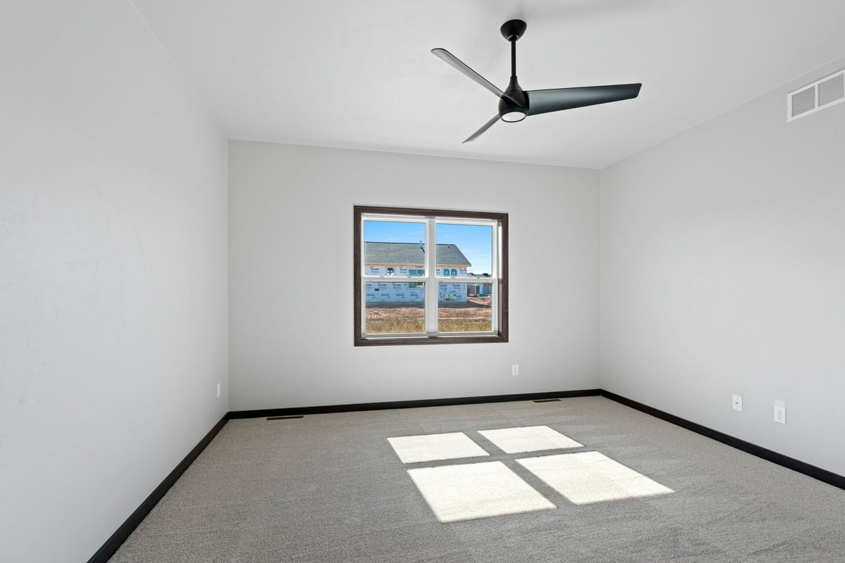 Bright bedroom with ceiling fan and large window in a Midwest Design Homes custom home in Harrison, WI.