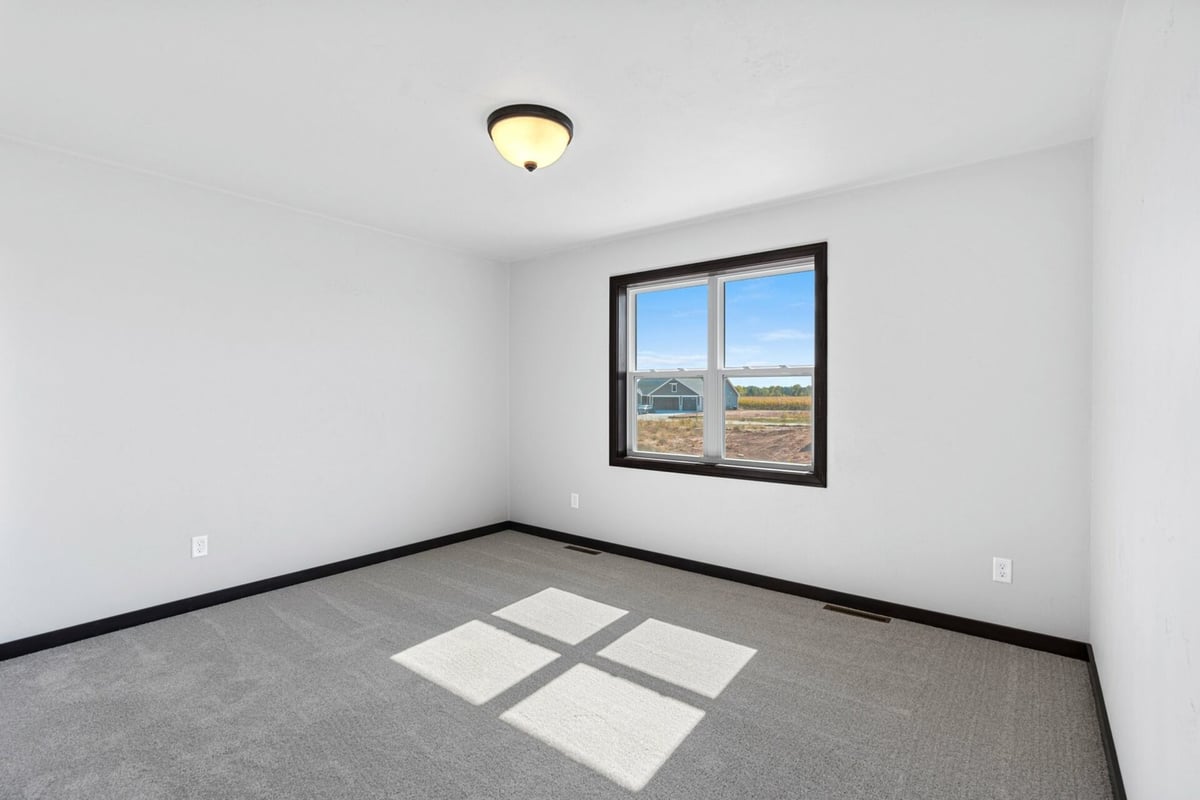 Clean and neutral bedroom with large window in a Midwest Design Homes custom home in Lawrence, WI.