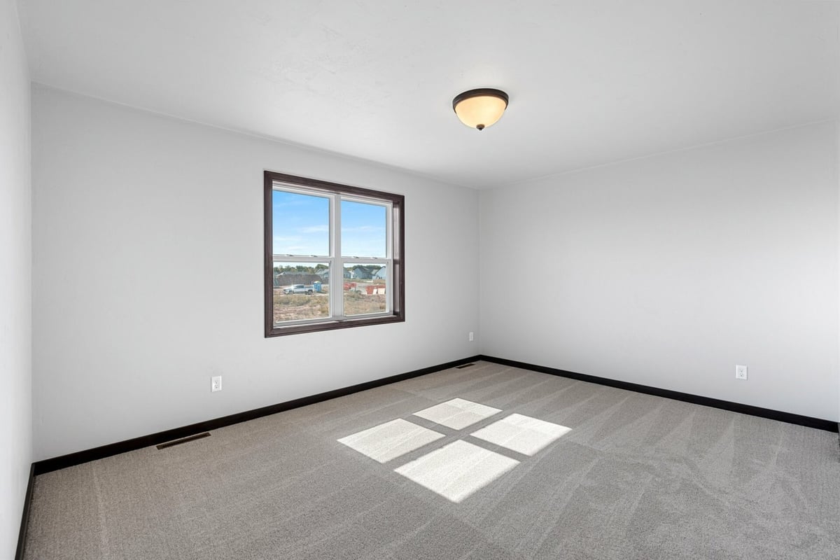 Custom home bedroom with modern base trim and ceiling light by Midwest Design Homes in Harrison, WI.