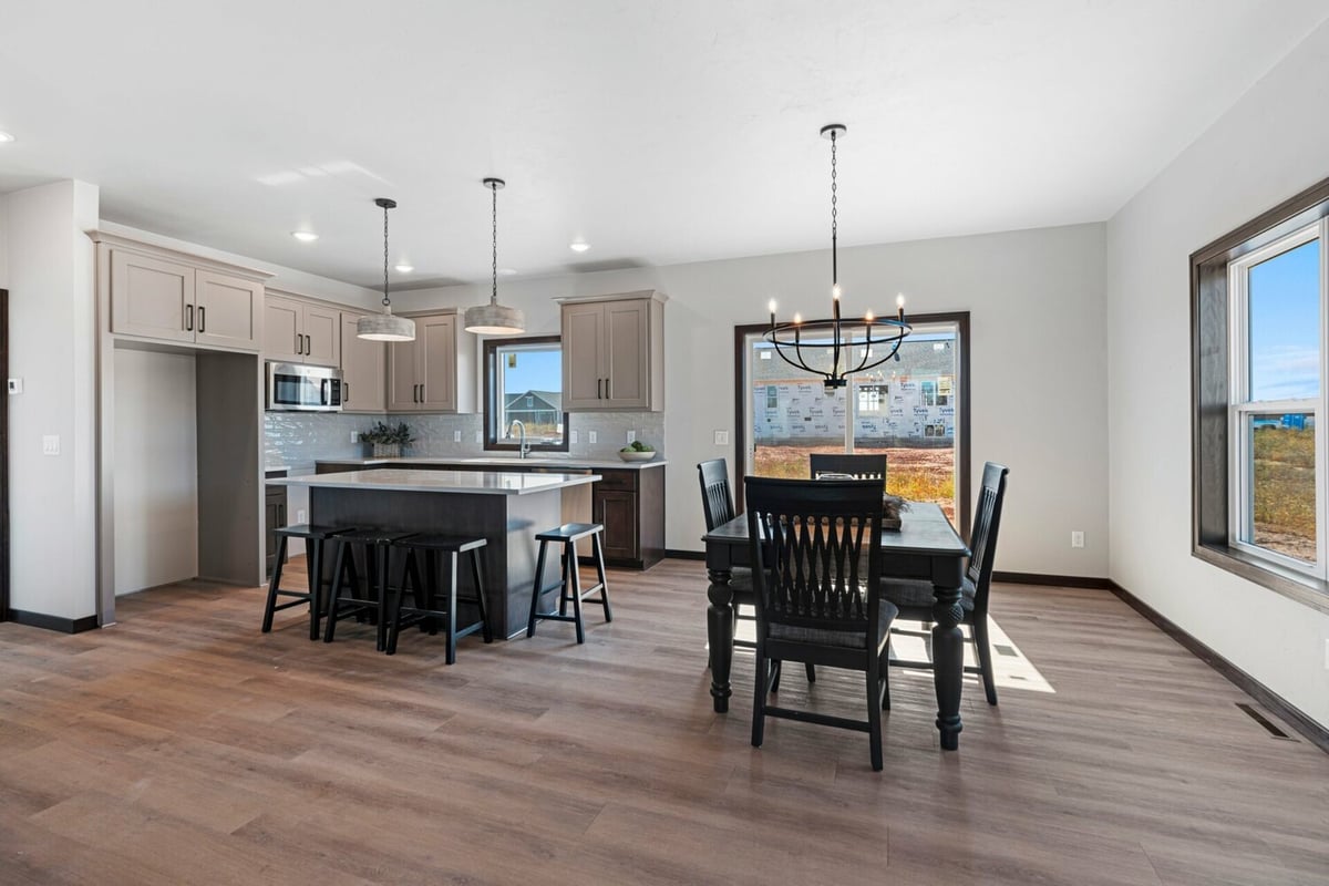 Dining area with large windows and custom kitchen in a Midwest Design Homes house in Greenville, WI.