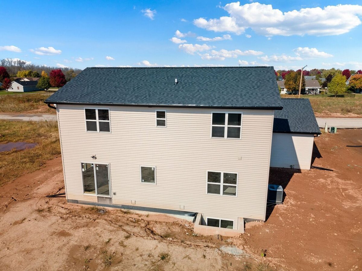 Rear exterior of a two-story custom home by Midwest Design Homes in Bellevue, WI with unfinished yard.