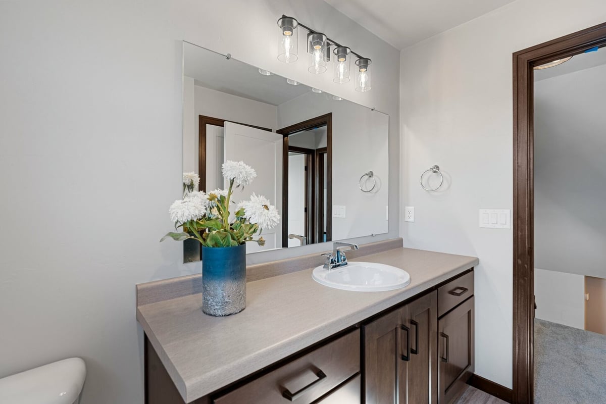 Sleek bathroom layout with flower vase and dark wood cabinetry in a Midwest Design Homes custom home in Harrison, WI.