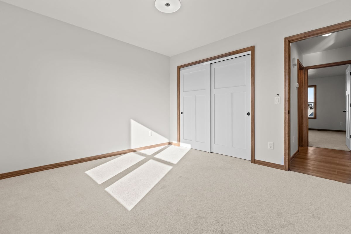 Bright bedroom with carpeted floors, sliding closet doors, and natural light, located in the Fox Cities