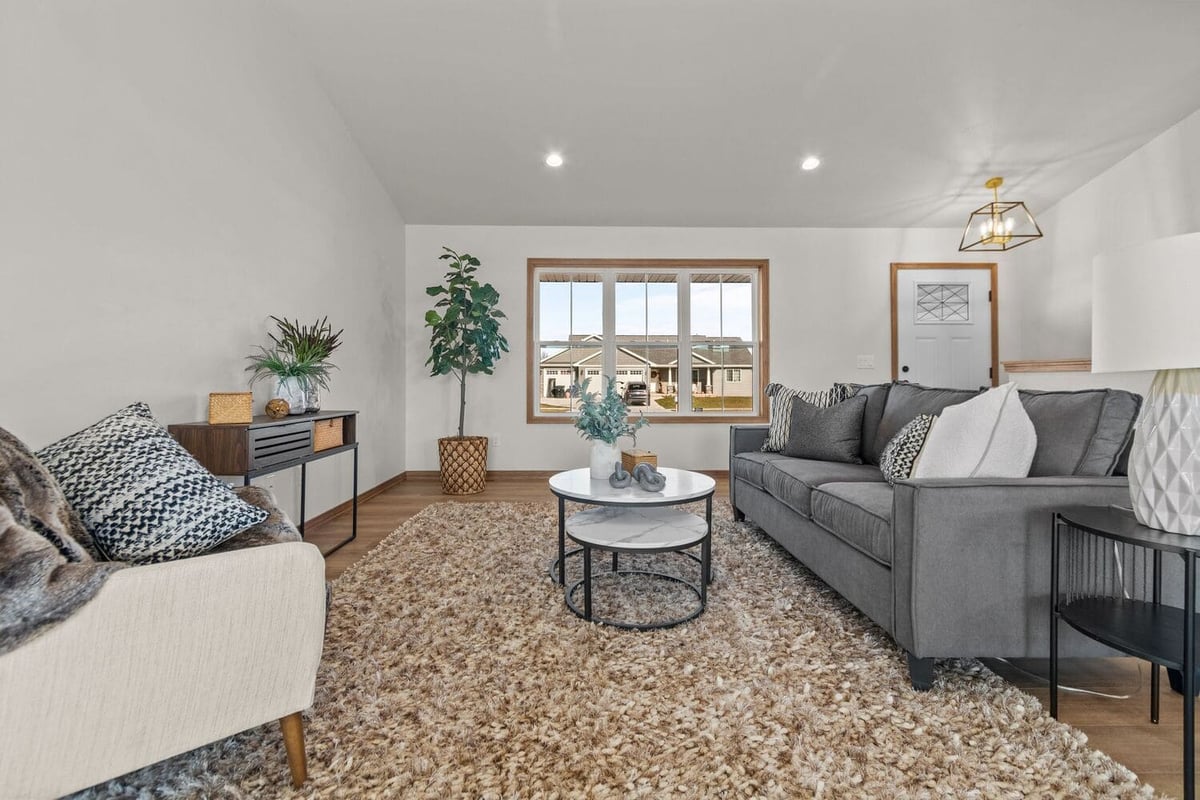 Bright living room with sofas, accent chairs, area rug, and large front window in a modern home located in the Fox Cities