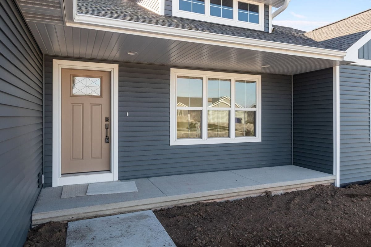 Covered front porch with entry door, siding, and windows on a new home exterior, located in the Fox Cities