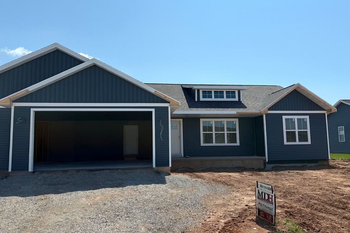 Custom home under construction with blue siding and attached garage by Midwest Design Homes in Kaukauna, WI