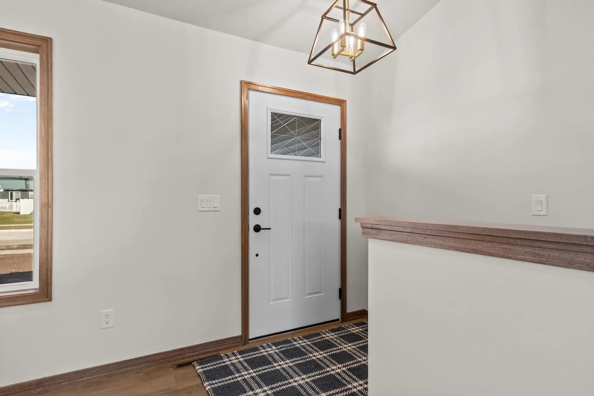 Front entryway with white door, modern light fixture, and wood trim, located in the Fox Cities