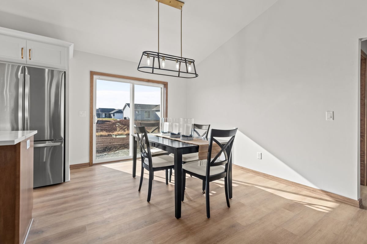Dining area with table seating, modern light fixture, and sliding glass door, located in the Fox Cities