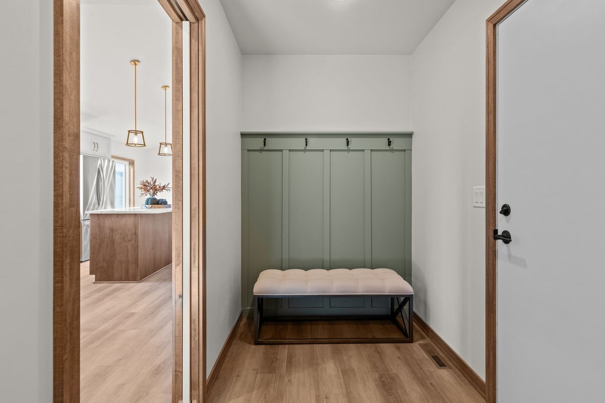 Mudroom with built-in bench, green shiplap accent, coat hooks, and wood-look flooring, located in the Fox Cities