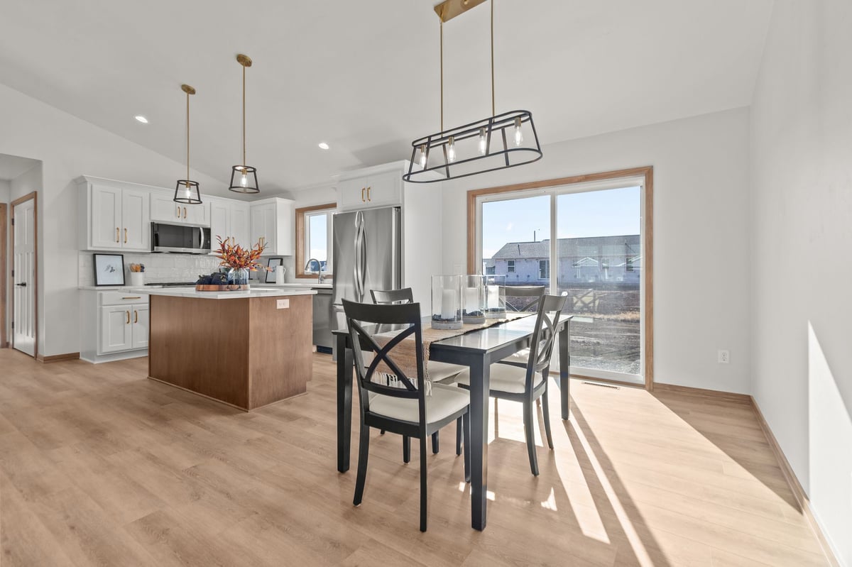 Open kitchen and dining area with island, pendant lighting, and patio door, located in the Fox Cities