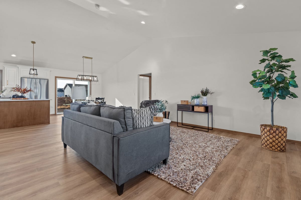 Open living room with vaulted ceiling, staged seating, and adjacent kitchen and dining area, located in the Fox Cities