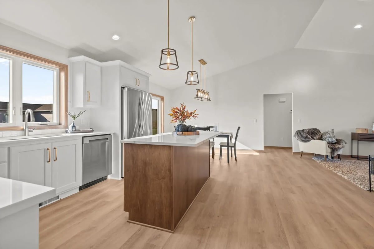 Open-concept kitchen and dining area with large island, pendant lighting, and wood floors, located in the Fox Cities