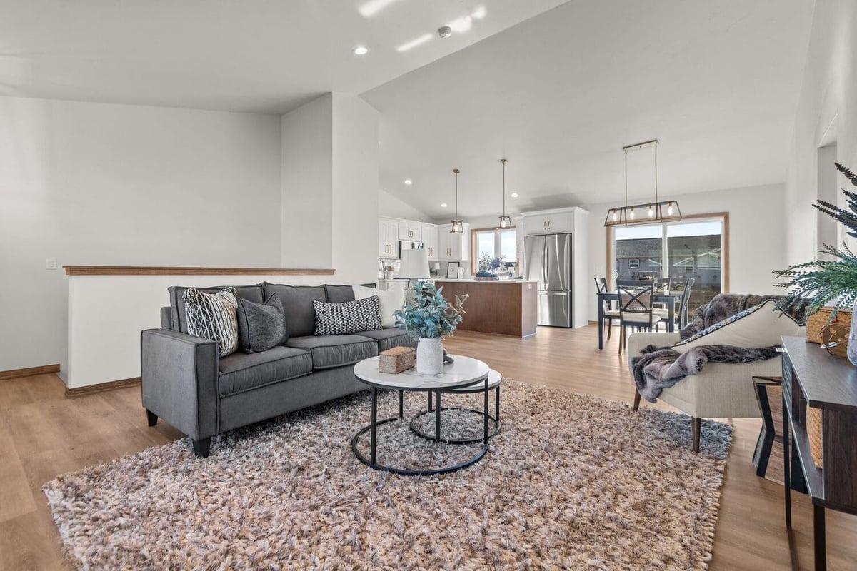 Open-concept living room with sofa, chairs, and view into kitchen and dining area, located in the Fox Citie
