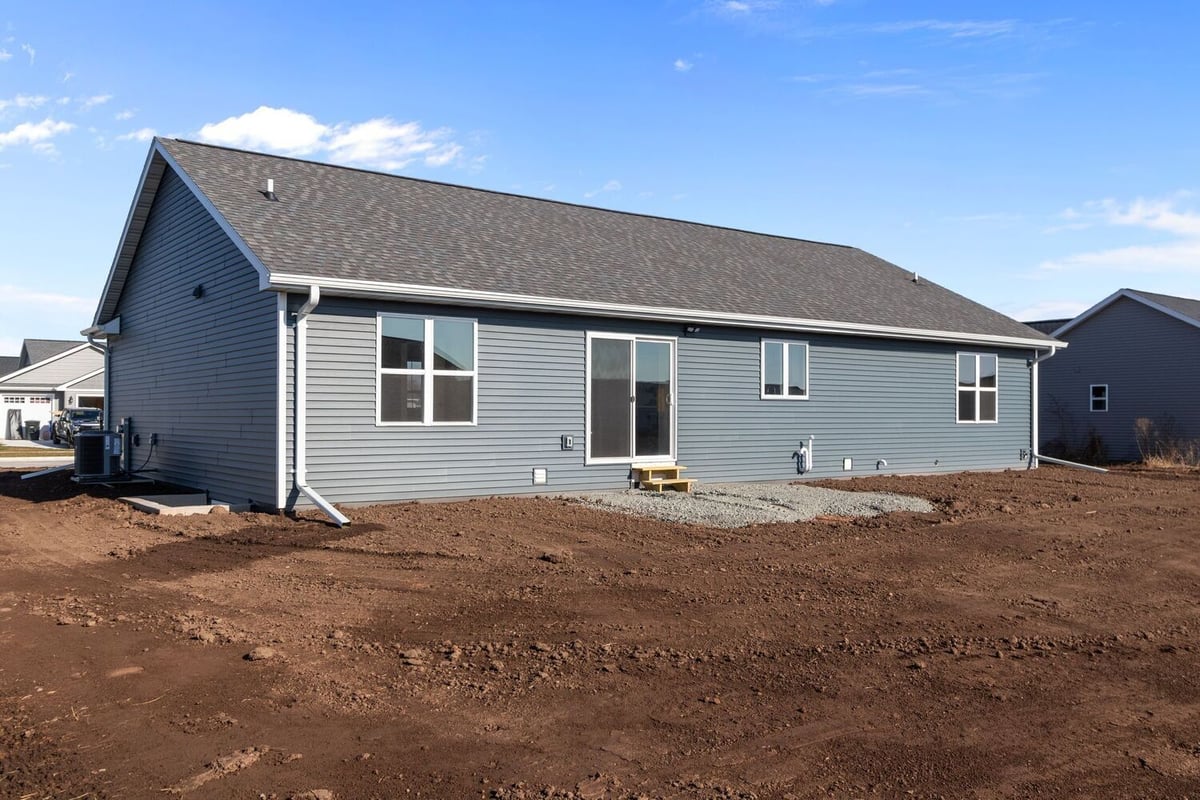 Rear view of a new single-story home with a large graded backyard in a developing neighborhood, located in the Fox Cities