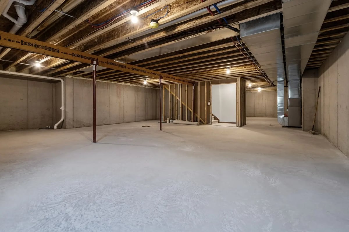 Unfinished basement with concrete floors, exposed beams, support posts, and utility access, located in the Fox Cities
